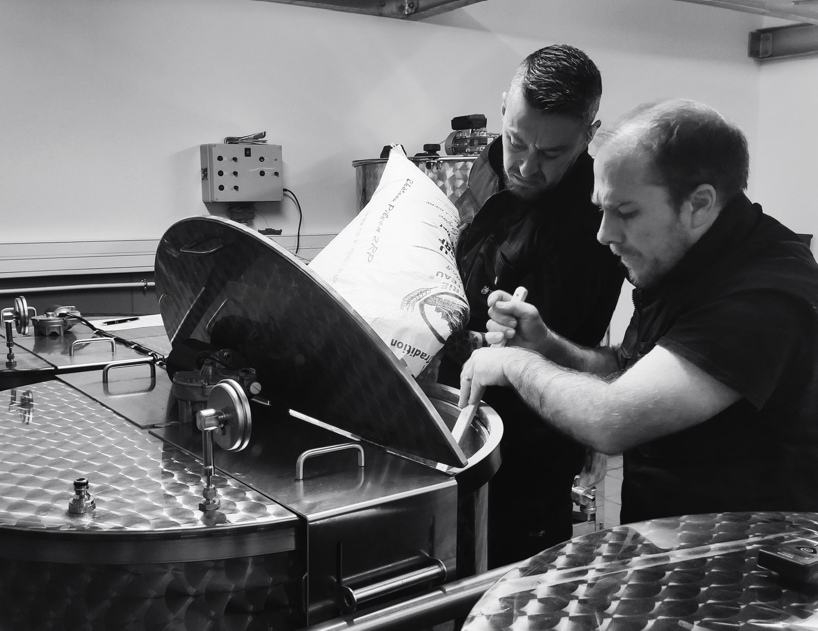 Les deux brasseurs versant le malt dans la cuve d'empâtage